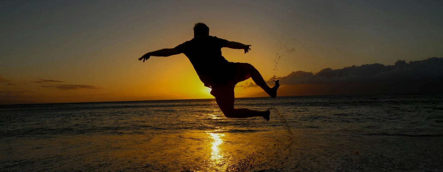 a man in silhouette jumping for joy on a beach at sunset, representing firefish's double award win at the market research society awards 2016
